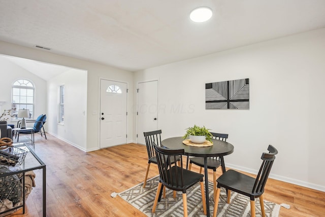 dining room with vaulted ceiling, visible vents, light wood-type flooring, and baseboards