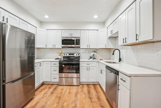 kitchen featuring a sink, light countertops, light wood finished floors, and stainless steel appliances