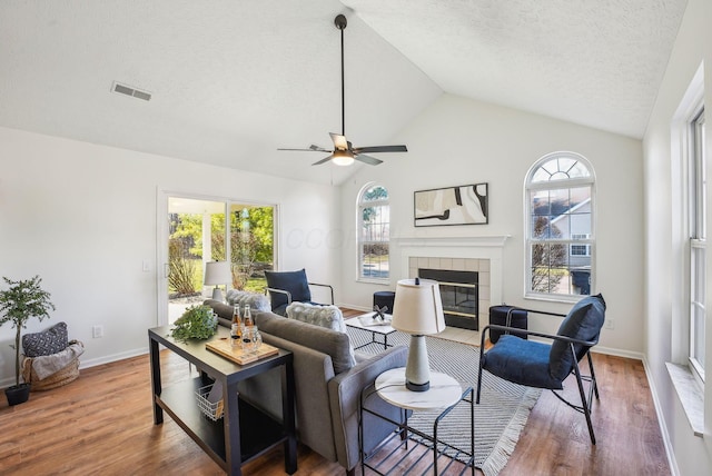 living room featuring ceiling fan, visible vents, wood finished floors, and a fireplace