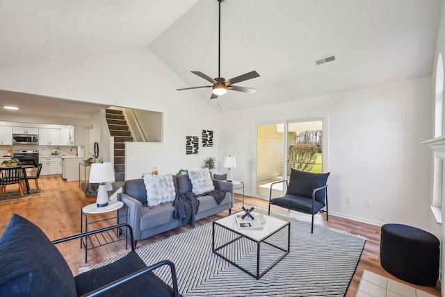 living area with light wood-type flooring, visible vents, baseboards, and ceiling fan