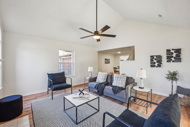 living room featuring vaulted ceiling, baseboards, ceiling fan, and wood finished floors