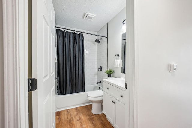 full bathroom with visible vents, shower / bath combo with shower curtain, vanity, wood finished floors, and a textured ceiling