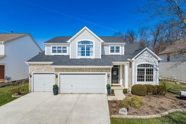 traditional-style home featuring stone siding, driveway, a shingled roof, and an attached garage