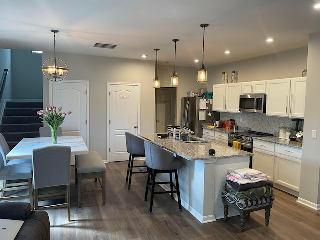 kitchen featuring visible vents, a sink, decorative backsplash, stainless steel appliances, and white cabinets