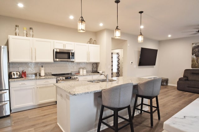 4835 Amber Crossing Dr, Columbus, OH 43232 - kitchen featuring a sink, tasteful backsplash, open floor plan, stainless steel appliances, and light wood-style floors