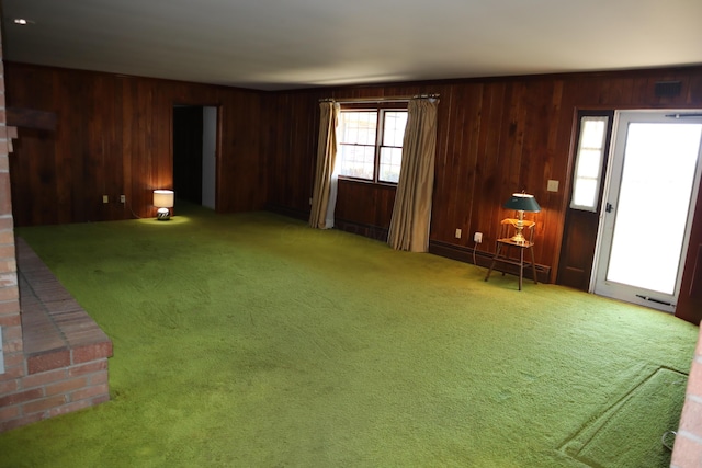 unfurnished living room with carpet flooring, visible vents, and wood walls