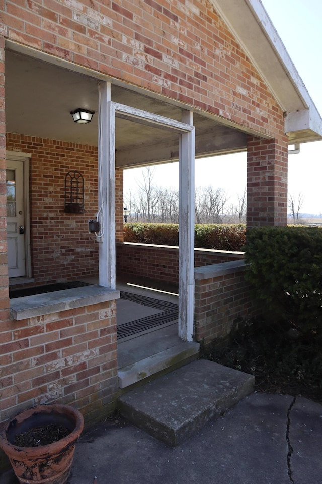 property entrance with covered porch and brick siding