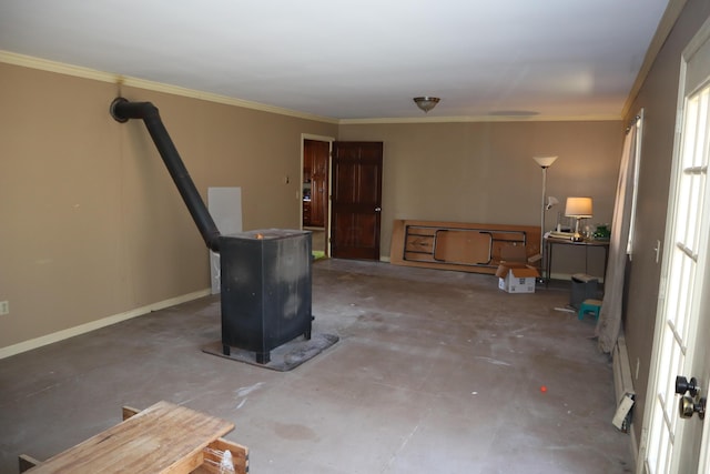 interior space with ornamental molding, a baseboard heating unit, unfinished concrete flooring, baseboards, and a wood stove