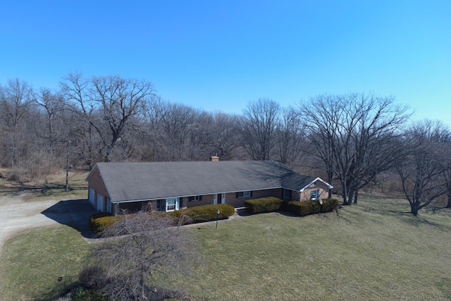 single story home with a garage, driveway, a chimney, and a front yard