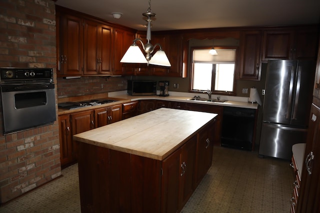 kitchen with a sink, decorative light fixtures, a center island, appliances with stainless steel finishes, and wooden counters