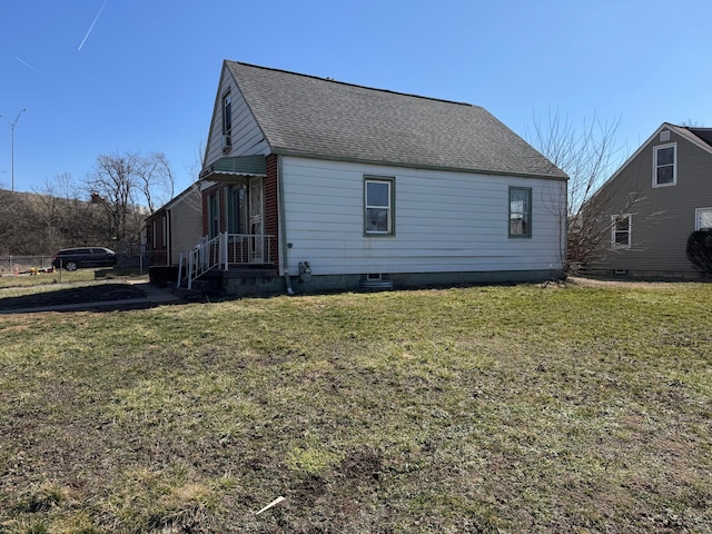 view of property exterior with a shingled roof and a yard