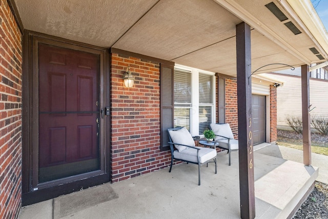 view of exterior entry with brick siding and a porch