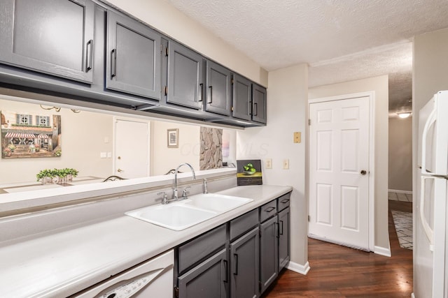 kitchen featuring gray cabinets, a sink, white appliances, light countertops, and dark wood-style flooring