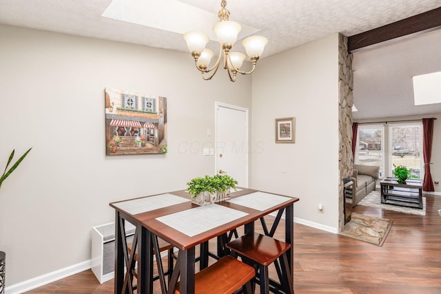 dining room featuring baseboards, a textured ceiling, an inviting chandelier, and wood finished floors