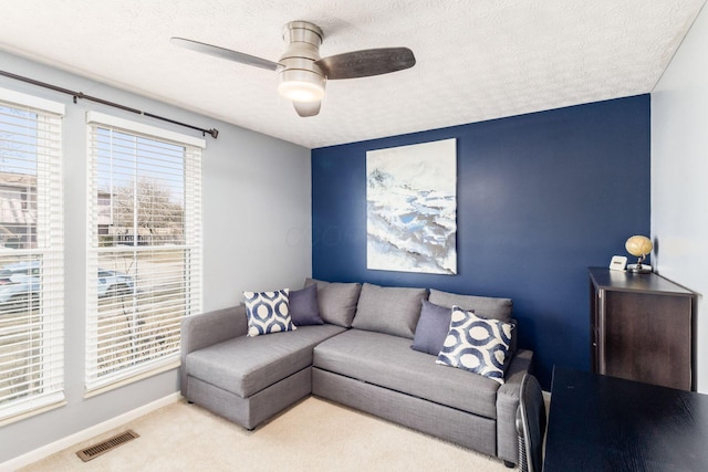 carpeted living area with visible vents, baseboards, a textured ceiling, and ceiling fan