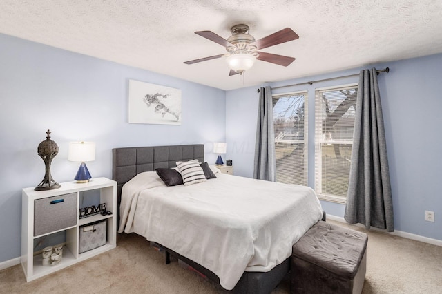 bedroom with ceiling fan, light colored carpet, baseboards, and a textured ceiling