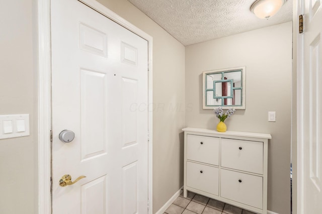 interior space with tile patterned flooring, a textured ceiling, and baseboards