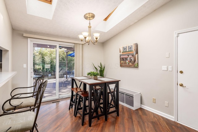 dining space with a chandelier, visible vents, vaulted ceiling with skylight, and wood finished floors