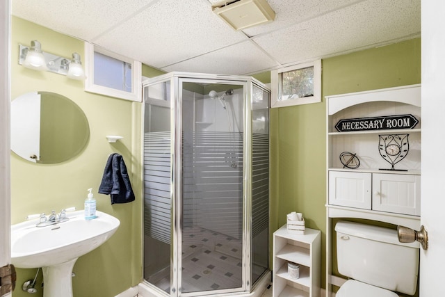 bathroom with a shower stall, toilet, a paneled ceiling, and a sink