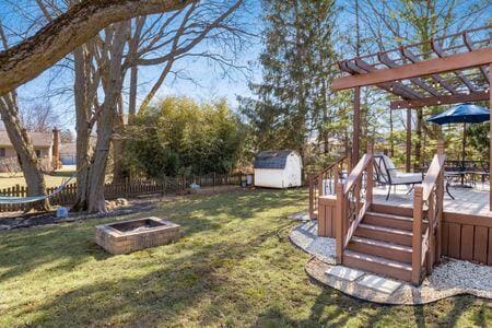 view of yard featuring fence, a shed, a pergola, an outdoor structure, and a fire pit