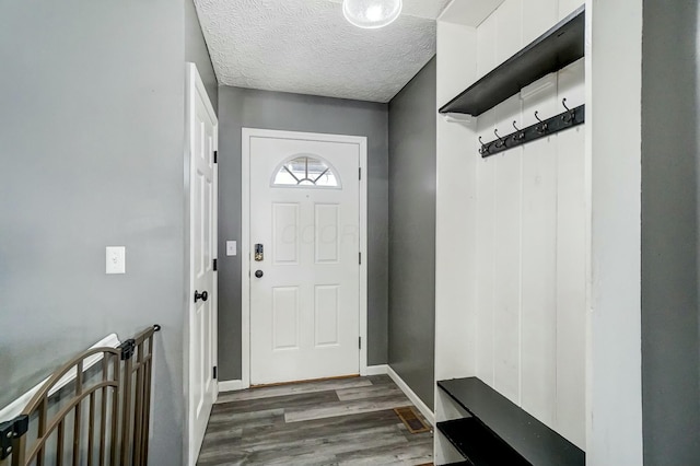 mudroom featuring a textured ceiling, baseboards, and wood finished floors