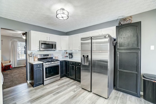 kitchen with decorative backsplash, white cabinets, appliances with stainless steel finishes, and light countertops