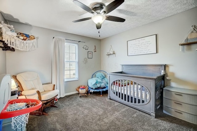 bedroom featuring a ceiling fan, baseboards, carpet floors, a crib, and a textured ceiling