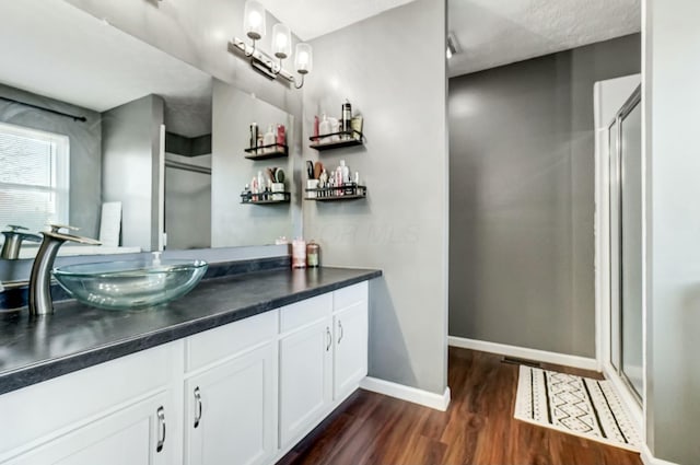 bathroom with a shower stall, vanity, baseboards, and wood finished floors