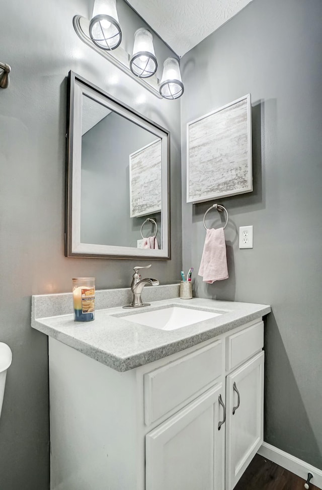 bathroom with vanity, baseboards, and wood finished floors