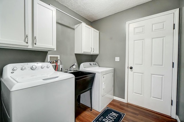 laundry area featuring baseboards, washer and clothes dryer, dark wood finished floors, cabinet space, and a textured ceiling