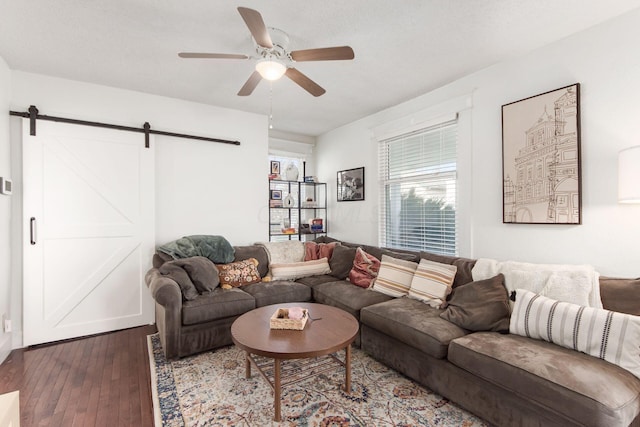 living room with a barn door, a ceiling fan, and wood-type flooring