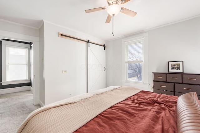 bedroom featuring ornamental molding, a barn door, carpet flooring, baseboards, and ceiling fan