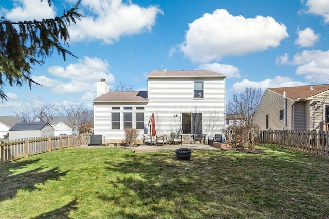 back of property with an outdoor fire pit, a lawn, a chimney, a fenced backyard, and a patio