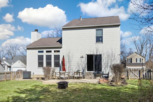 back of house featuring a gate, central AC, a fire pit, a patio area, and a lawn