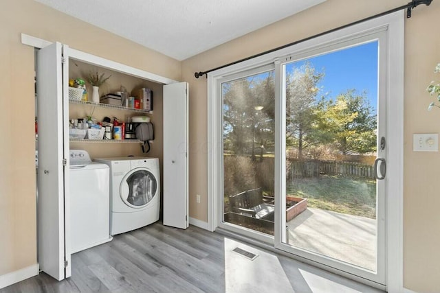 laundry room with a wealth of natural light, independent washer and dryer, wood finished floors, and laundry area