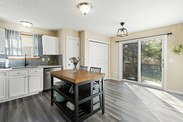 kitchen with a sink, backsplash, white cabinetry, dishwasher, and dark wood-style flooring