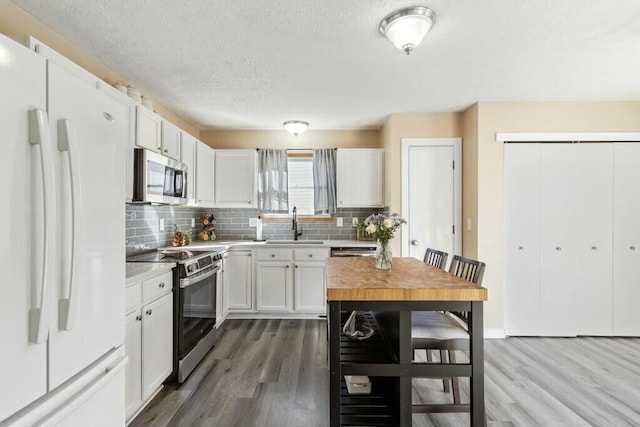 kitchen featuring white cabinetry, wood finished floors, and stainless steel appliances