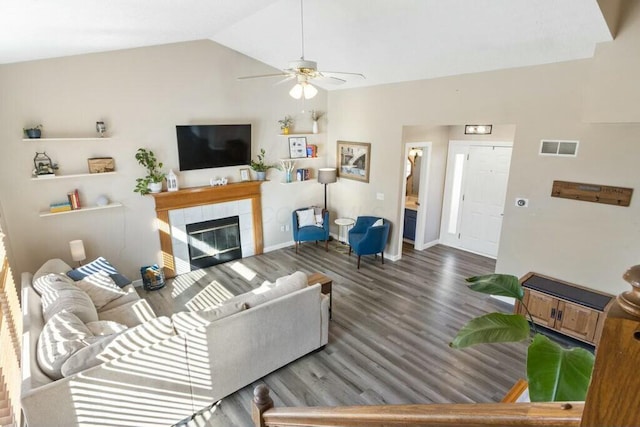 living area with visible vents, ceiling fan, vaulted ceiling, a tile fireplace, and wood finished floors