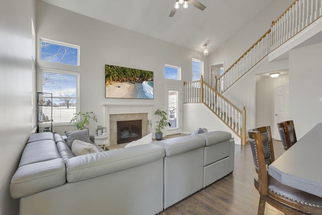 living room featuring stairway, a ceiling fan, high vaulted ceiling, dark wood finished floors, and a fireplace