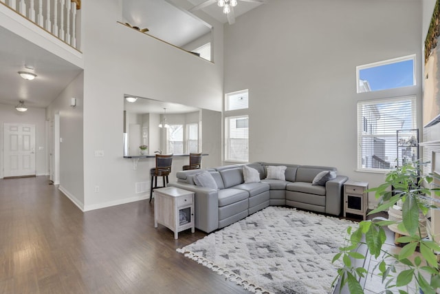 living area with plenty of natural light, a ceiling fan, baseboards, and dark wood-style flooring