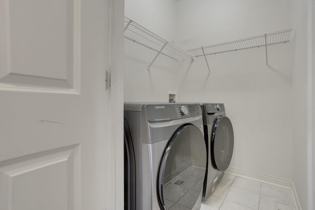 washroom with laundry area, light tile patterned floors, baseboards, and washing machine and clothes dryer