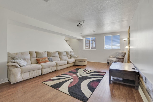 living room featuring wood finished floors, baseboards, and a textured ceiling