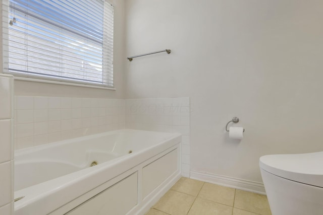 full bathroom with tile patterned floors, a jetted tub, toilet, and baseboards