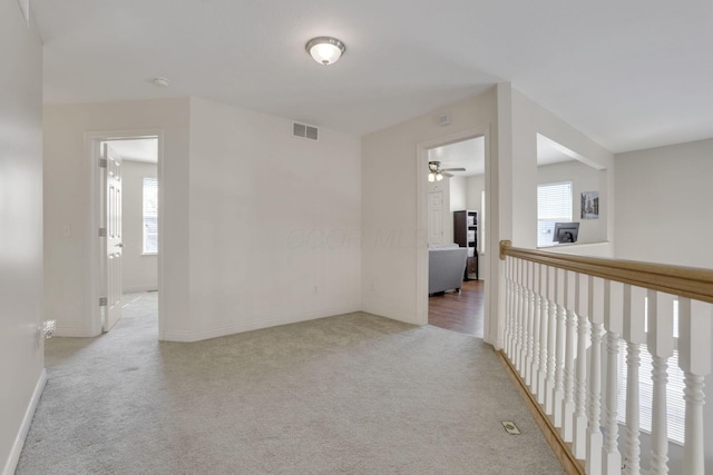 hallway with visible vents, baseboards, and carpet floors