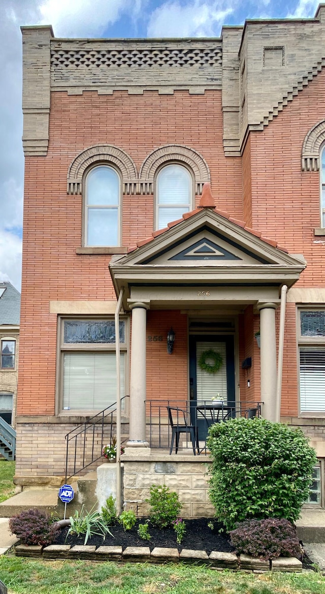 entrance to property featuring a porch and brick siding