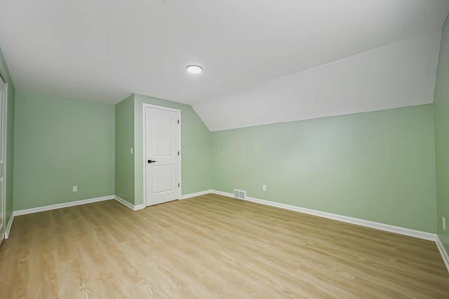 bonus room with light wood finished floors, visible vents, lofted ceiling, and baseboards