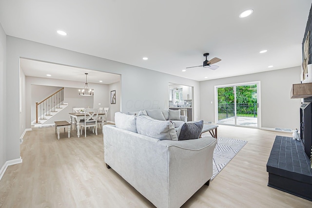 living area with ceiling fan with notable chandelier, recessed lighting, light wood-style floors, and baseboards