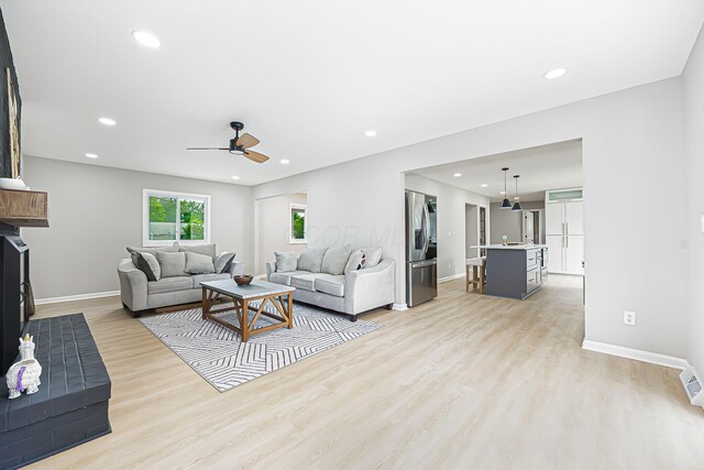 living room with recessed lighting, baseboards, light wood-style floors, and a ceiling fan