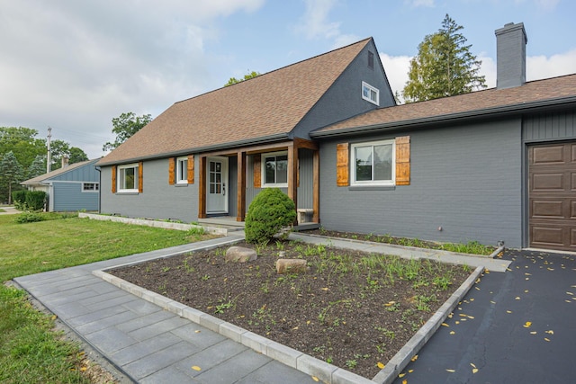 view of front of home featuring brick siding, a front lawn, a porch, roof with shingles, and an attached garage