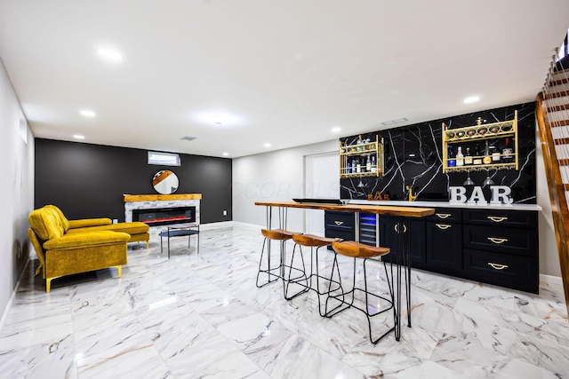 bar featuring a glass covered fireplace, recessed lighting, and marble finish floor